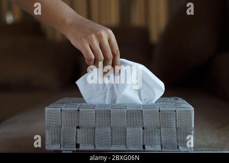 Nahaufnahme der Hand weiblich Kommissionierung ein weißes Seidenpapier aus grauen Box. Stockfoto