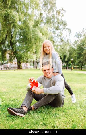 Vatertag. Glückliche Familie Tochter umarmt Vater und lacht im Urlaub. Mädchen gab Papa ein Geschenk im Park Stockfoto