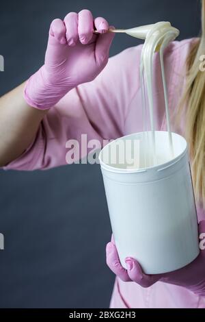 Der Arzt zieht rosa Schutzhandschuhe an, Nahaufnahme. Hände eines Sanitäter in rosa Uniform. Gießt Creme vor dem medizinischen Eingriff. Stockfoto