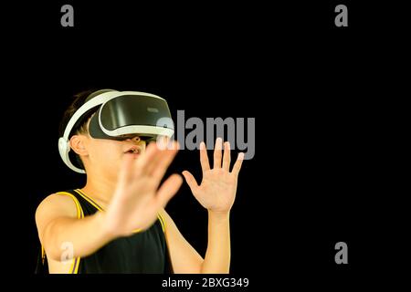 Teenager mit medizinischen Maske Spiel mit Virtual Reality-Headset isoliert. Stockfoto