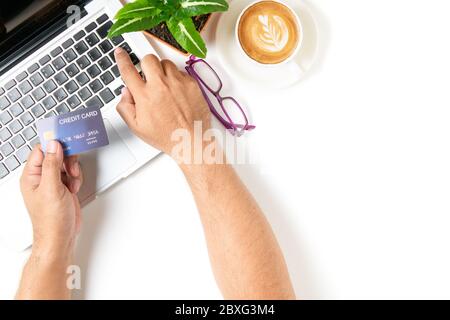 Mann mit Kreditkarte für Online-Shopping auf weißem Tisch mit Latte Art heißer Kaffee isoliert auf weißem Hintergrund, Draufsicht und Kopierer Raum für in Put te Stockfoto