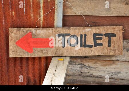 Schilder zu den Toiletten, die auf einem Sperrholzblatt geschrieben wurde. Stockfoto