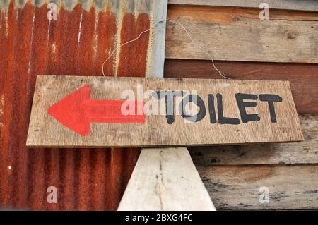 Schilder zu den Toiletten, die auf einem Sperrholzblatt geschrieben wurde. Stockfoto