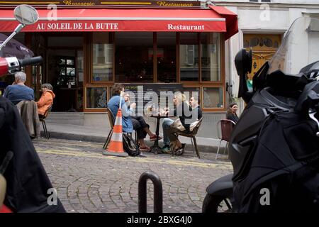 Die Menschen genießen einen Drink auf einer temporären Café-Terrasse, auf einem Parkplatz, im Leben nach der Sperre - Rue Muller, Montmartre, 75018 Paris, Frankreich Stockfoto