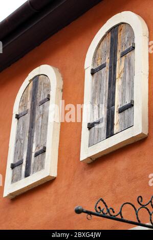 Holzfenster im europäischen Stil, abgerundete Ecken an der braunen Wand. Stockfoto