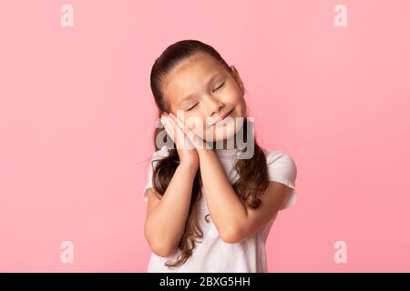 Schöne kleine asiatische Mädchen mit glücklich heiteren Gesicht vorgibt zu schlafen Stockfoto