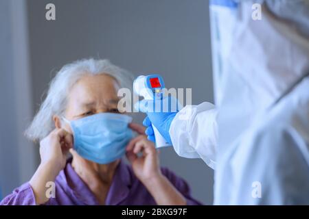Arzt, der die Temperatur einer älteren Frau mit einem Infrarot-Thermometer überprüft, Thailand Stockfoto