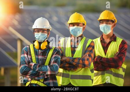 Drei Ingenieure in einer Solaranlage mit Gesichtsmasken, Thailand Stockfoto