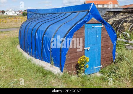 Alte Fischerboote umgedreht geschnitten und als Lagerhallen auf Lindisfarne, Northumberland, England verwendet Stockfoto