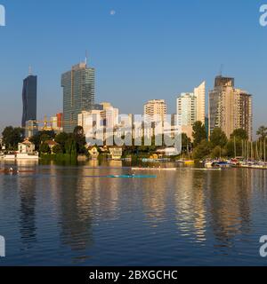 WIEN, ÖSTERREICH - 1. SEPTEMBER 2015: Gebäude in der Nähe des Danau Parks in Wien am Morgen. Man kann Leute im Wasser rudern sehen. Stockfoto