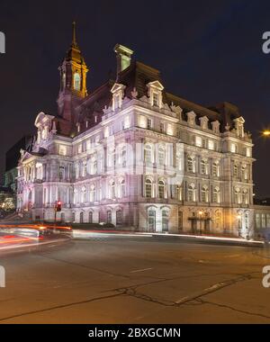 Blick auf das Rathaus von Montreal (Hôtel de Ville de Montréal) bei Nacht. Die Unschärfe des Verkehrs ist zu sehen. Es ist Platz für Text. Stockfoto