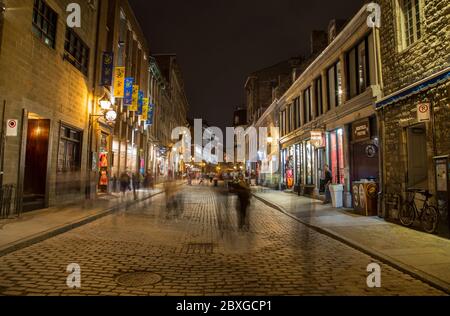 MONTREAL, KANADA - 17. MAI 2015: Gebäude und Geschäfte entlang der Rue Saint Paul in der Altstadt von Montreal bei Nacht. Die Unschärfe der Menschen ist zu sehen. Stockfoto