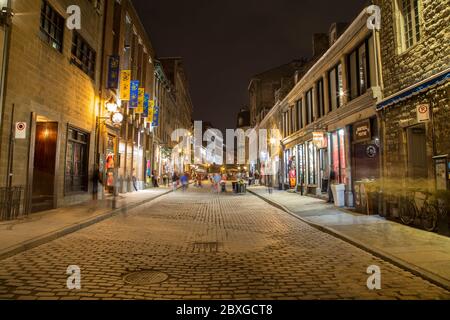 MONTREAL, KANADA - 17. MAI 2015: Gebäude und Geschäfte entlang der Rue Saint Paul in der Altstadt von Montreal bei Nacht. Die Unschärfe der Menschen ist zu sehen. Stockfoto