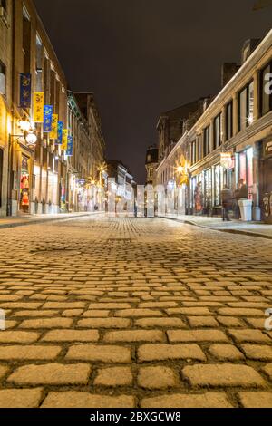 MONTREAL, KANADA - 17. MAI 2015: Gebäude und Geschäfte entlang der Rue Saint Paul in der Altstadt von Montreal bei Nacht. Die Unschärfe der Menschen ist zu sehen. Stockfoto