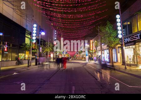 MONTREAL KANADA - 17. MAI 2015: Ein Blick auf die St. Catherine Street in Montreal bei Nacht zeigt Geschäfte und die Unschärfe der Menschen. Stockfoto