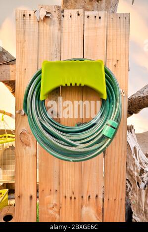 Schläuche werden in der Lagerung, die im Garten aufgerollt Stockfoto