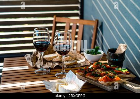 Zwei Gläser Rotwein mit Antipasto-Snacks auf einem Tisch im Freien Stockfoto