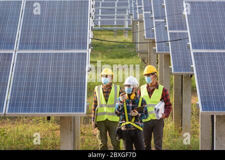 Drei Ingenieure in einer Solaranlage mit Gesichtsmasken, Thailand Stockfoto