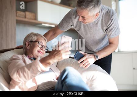 Glückliche ältere Paare sprechen über Video-Link in ihrem Wohnzimmer. Stockfoto