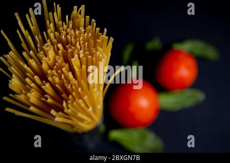Spaghetti Paste, Tomaten und andere Produkte zum Kochen auf dunklem Hintergrund Draufsicht. Platz für Text, Draufsicht Stockfoto