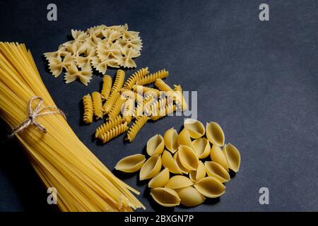 Verschiedene Arten von Pasta auf schwarzem Hintergrund. Ansicht von oben. Verschiedene Formen der Pasta. Kopieren Sie Raum für Design. Stockfoto
