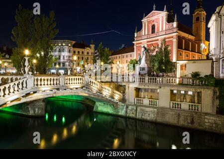 LJUBLJANA, SLOWENIEN - 26. MAI 2016: Franziskanerkirche der Verkündigung, Dreifachbrücken und andere Gebäude in Ljubljana bei Nacht Stockfoto