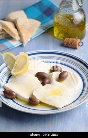 In Scheiben geschnittenen Mozzarella mit kalamata Oliven, Olivenöl, Zitronenscheiben und pita auf einer blauen Tabelle Stockfoto