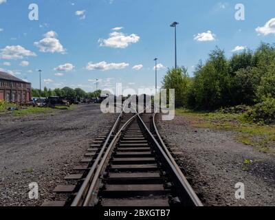 Eisenbahnschienen, die aus der Mitte der Gleise genommen wurden, mit Blick auf alte verlassene Eisenbahnwaggons, auf der East Lancashire Railway. Stockfoto