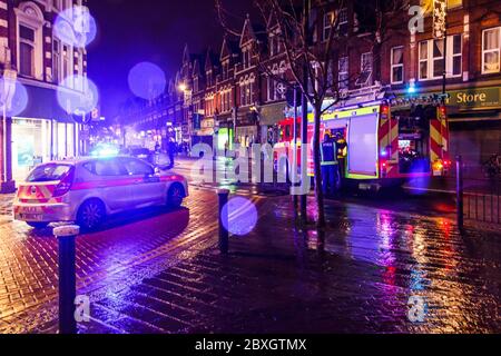 Ein Polizeiauto und ein Feuerwehrauto nehmen an einem Autobrand an einem regnerischen Herbstabend in Crouch End, London, Großbritannien Teil Stockfoto