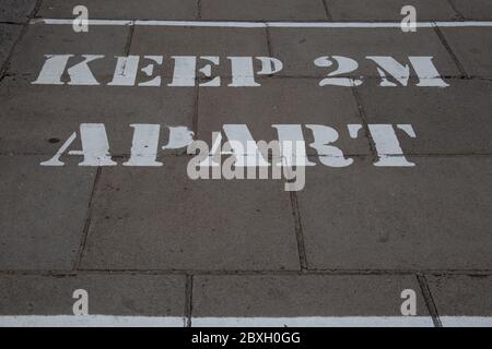 Schild auf dem Bürgersteig erinnert die Menschen zwei Meter auseinander während der Corona Pandemie, Hammersmith West London UK bleiben Stockfoto