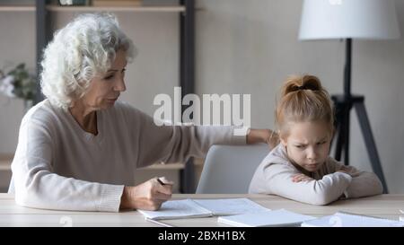 Kleines Mädchen fühlen unmotiviert Hausaufgaben mit Großeltern zu tun Stockfoto