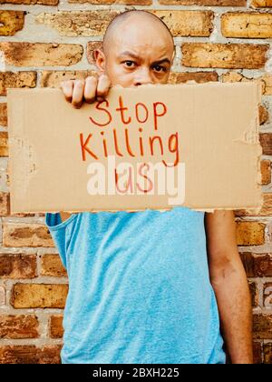 Ein schwarzer Mann hält ein Schild mit der Aufschrift "Stoop Killing US" hoch, um gegen die Brutalität der Polizei zu protestieren Stockfoto