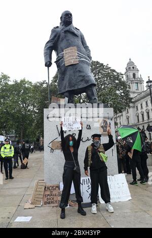 Protestler halten Plakate neben der Winston Churchill Statue während der Black Lives Matter Protestkundgebung auf dem Parliament Square, Westminster, London, in Erinnerung an George Floyd, der am 25. Mai während der Polizeigewahrsam in der US-Stadt Minneapolis getötet wurde. Stockfoto