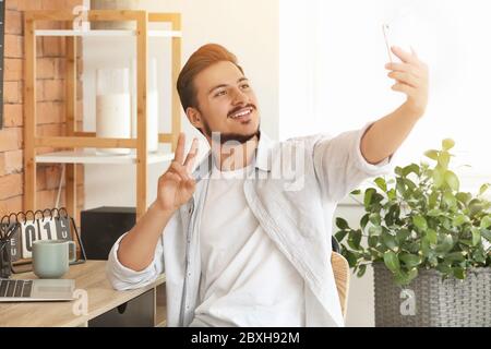 Schöner junger Mann, der zu Hause Selfie nimmt Stockfoto