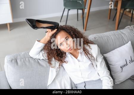 Unruhige Geschäftsfrau sitzt nach der Arbeit zu Hause auf dem Sofa Stockfoto