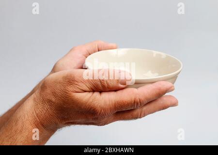 Der Mensch hält eine leere Schüssel in seinen Händen. Hilfe erforderlich Stockfoto