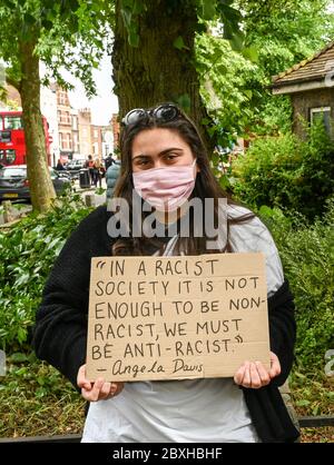 Eine junge Frau mit einem Plakat, die Angela Davis zitiert: "In einer rassistischen Gesellschaft reicht es nicht aus, nicht-rassistisch zu sein, wir müssen antirassistisch sein." Schwarze Leben sind wichtig. Stockfoto