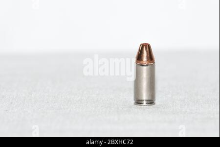 Eine einzelne 9 mm Kugel, die auf einer weißen Oberfläche steht. Nahaufnahme Stockfoto