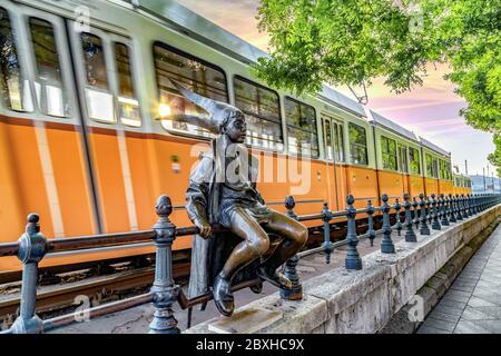 Budapest, Ungarn - Mai 20 2020 : die berühmte Donaupromenade in Pest, die Statue der Kleinen Prinzessin und die Straßenbahn Nummer 2, die gerade vorbeifährt. Stockfoto