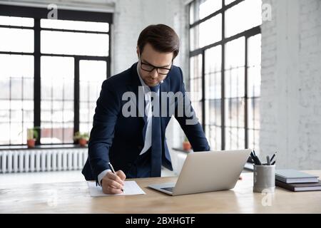 Seriöse Geschäftsmann arbeiten auf Laptop Notizen machen Stockfoto