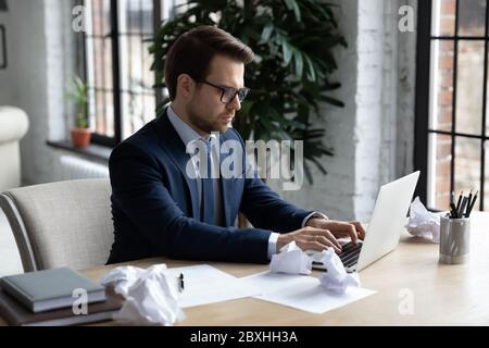 Männlicher Mitarbeiter, der im Büro mit dem Laptop beschäftigt ist Stockfoto