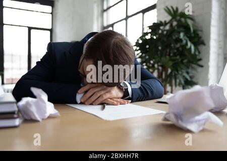 Erschöpfter Geschäftsmann schläft auf dem Schreibtisch im Büro ein Stockfoto