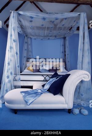 Blaues Schlafzimmer mit transparentem blauem Blumendruck Stoff mit Weiß Chaiselongue am Fuß des Bettes Stockfoto
