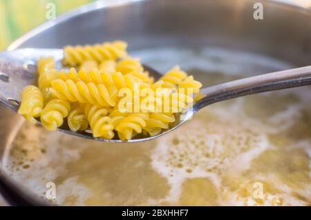 Pasta wird in einer Pfanne mit Kesselwasser und Spachtel gekocht Überprüfung auf Pasta Stockfoto