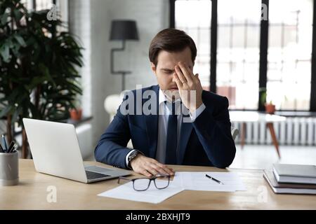 Müde Geschäftsmann leiden unter Kopfschmerzen am Arbeitsplatz Stockfoto