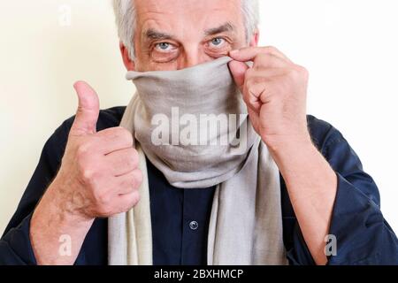 Der Mann zeigt, wie man aus einem normalen Schal eine Maske gegen einen Virus macht. Gesundheitswesen Stockfoto