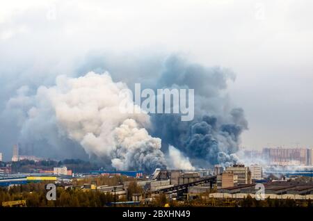 Feuer in Lagerhallen mit dunklen und weißen riesigen Rauchwolken Stockfoto