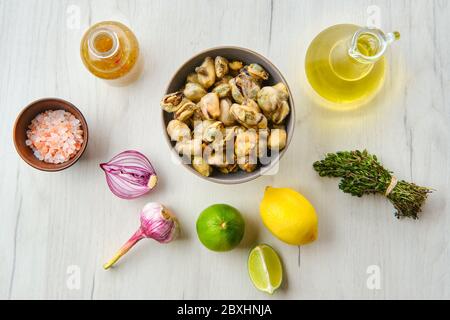 Draufsicht auf Muscheln in Schüssel mit Gewürzen und Kräutern Stockfoto