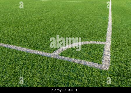 Grünes Gras und weiße Begrenzungs-Linien auf Fußballplatz. Fußballplatz auf Kunstrasen. Kunstrasen Textur. Künstliches Fußballfeld in einem Stockfoto