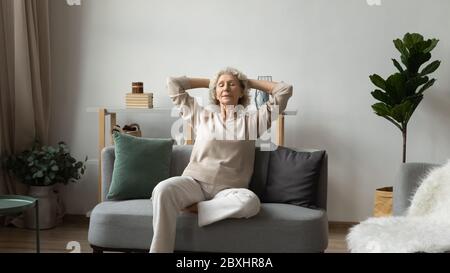 Friedliche ältere Frau entspannen auf der Couch meditieren Stockfoto